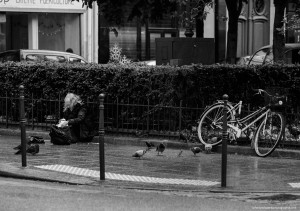 Une vieille dame assise sous la pluie sort un peu de pain de son sac. Peu importe qu'il fasse froid, qu'il pleuve ou qu'elle ne sache pas où dormir. Elle est heureuse de passer un peu de temps avec les seuls êtres qui sont proches d'elle.